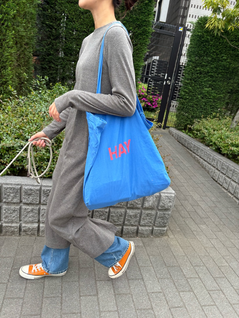 ブルー系のトートバッグ、グレー系のワンピース、オレンジ系のスニーカーを着用したレディースの春コーディネートの2枚目の写真