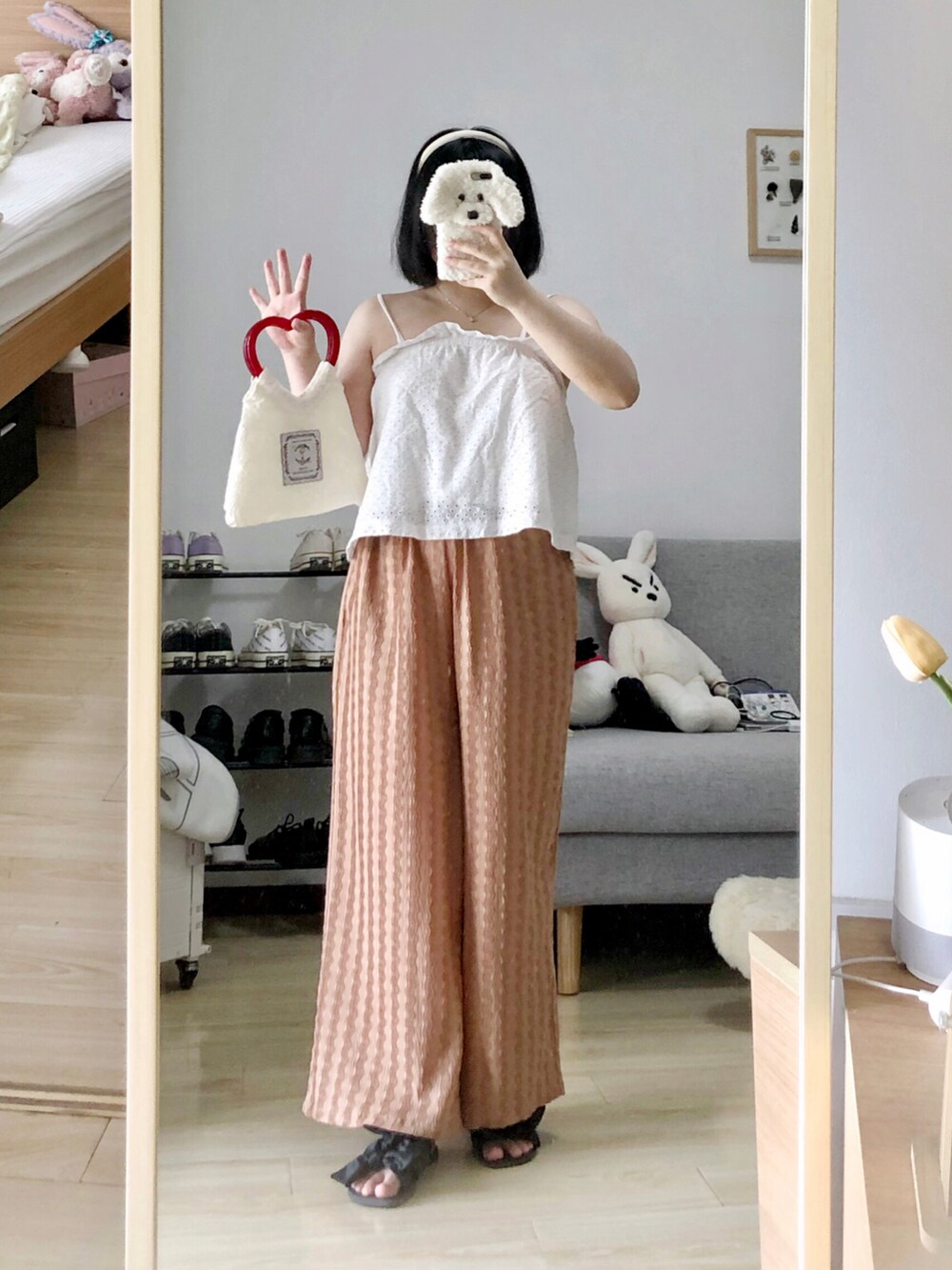 ホワイト系のトートバッグ、ブラウン系のチノパンツ、ホワイト系のタンクトップを着用したレディースの夏コーディネートの2枚目の写真