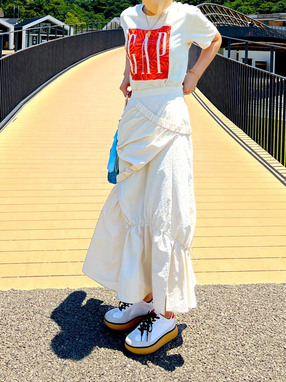 ベージュ系のTシャツ/カットソー、ホワイト系のスカート、ホワイト系のスニーカーを着用したレディースの夏コーディネートの2枚目の写真