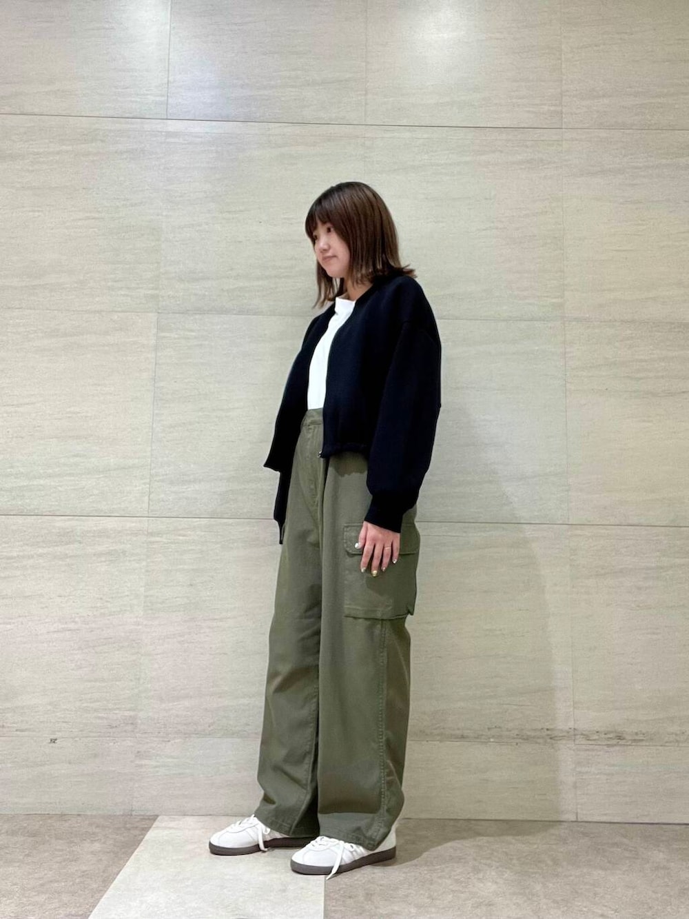 ホワイト系のTシャツ/カットソー、グリーン系のカーゴパンツ、ホワイト系のスニーカーを着用したレディースの秋コーディネートの2枚目の写真