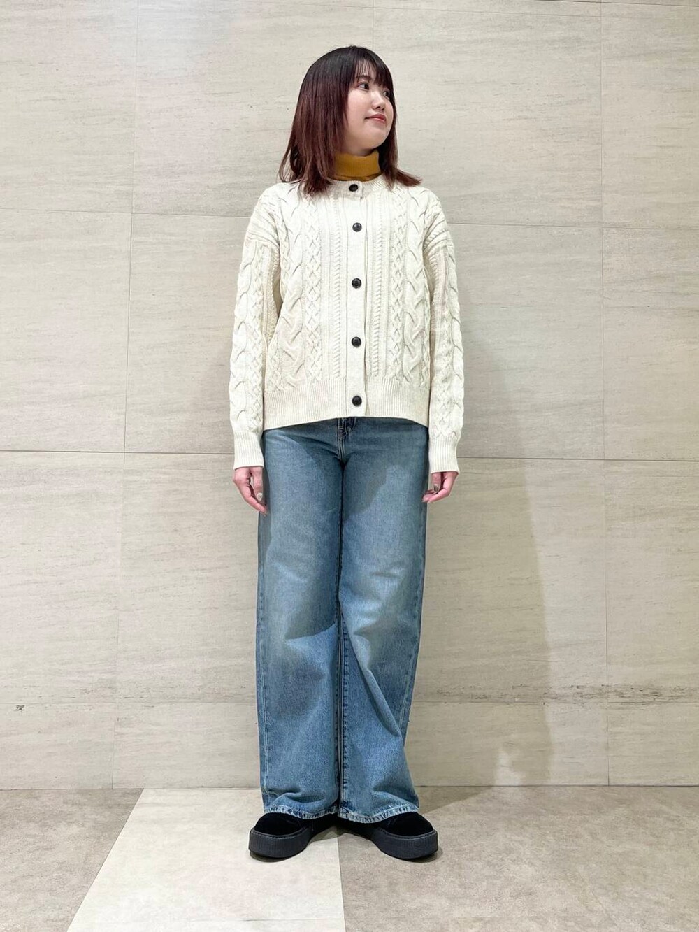 ホワイト系のカーディガン/ボレロ、イエロー系のニット/セーター、ブルー系のデニムパンツを着用したレディースの冬コーディネートの2枚目の写真