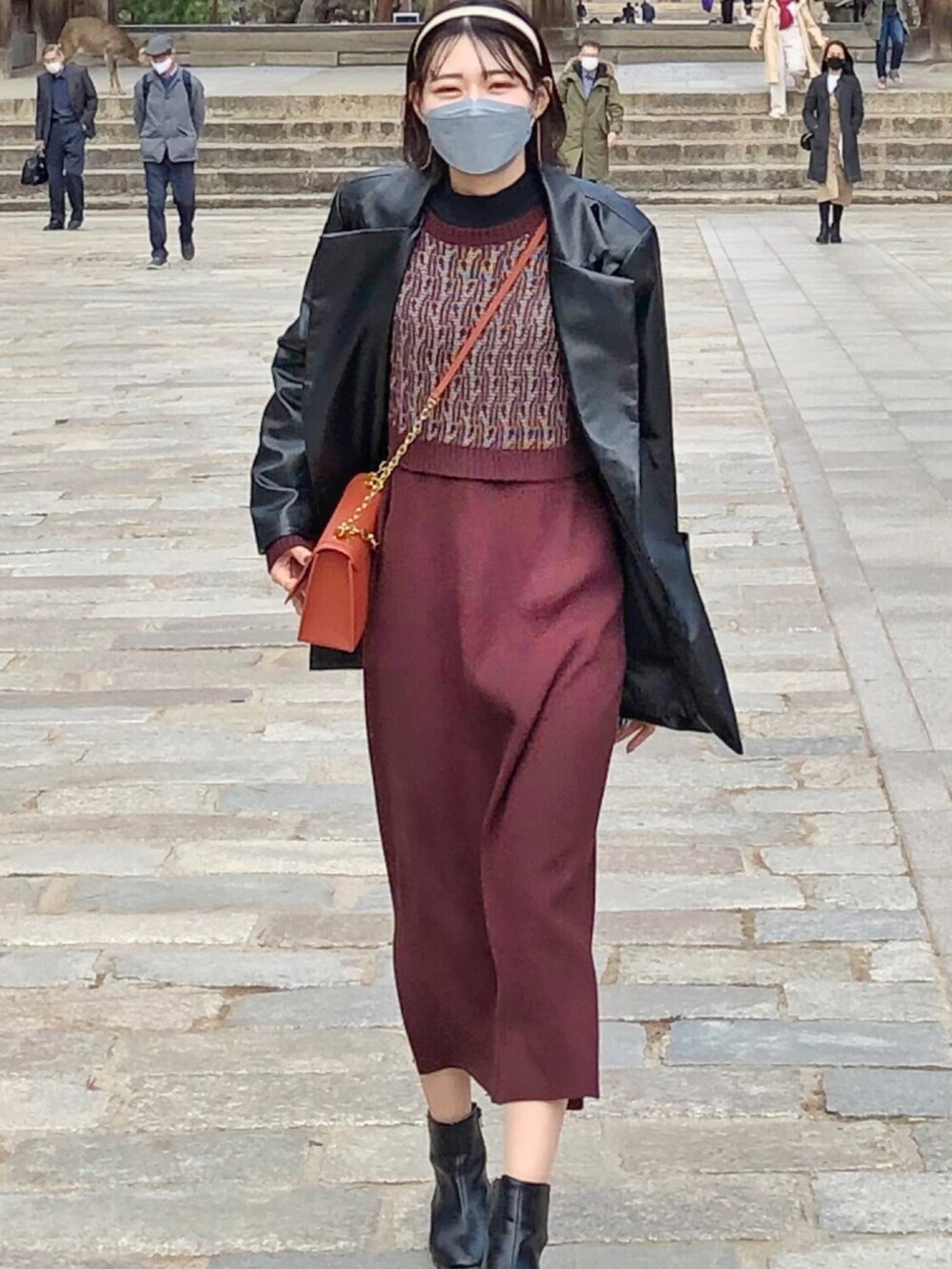 ブラック系のテーラードジャケット、ブラウン系のワンピースを着用したレディースの冬コーディネートの2枚目の写真