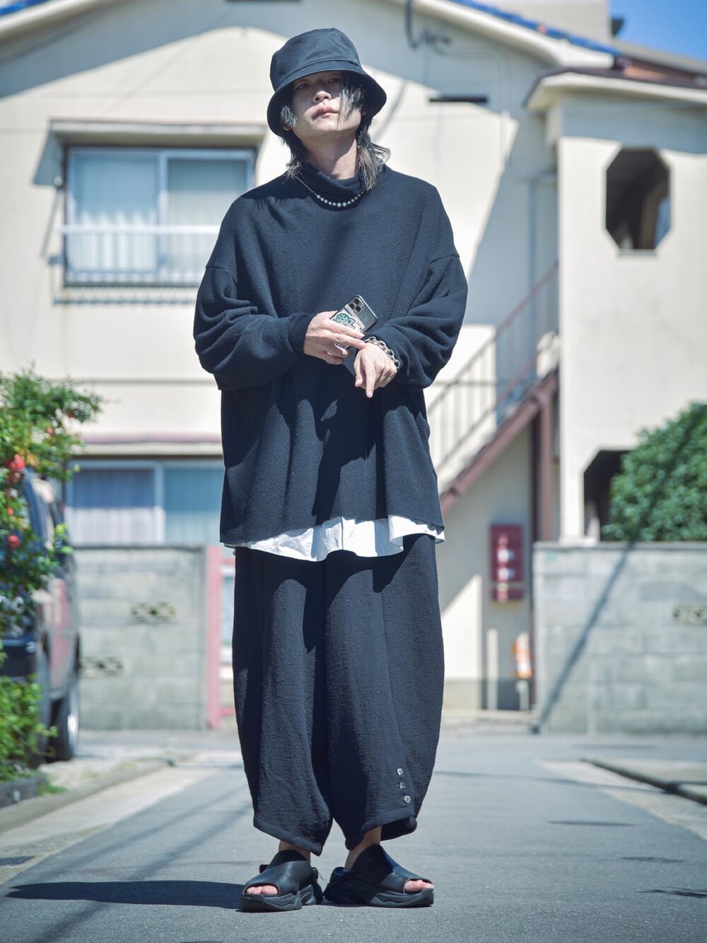 ブラック系のニット/セーター、ブラック系のパンツ、ブラック系のサンダルを着用したメンズの秋コーディネートの2枚目の写真