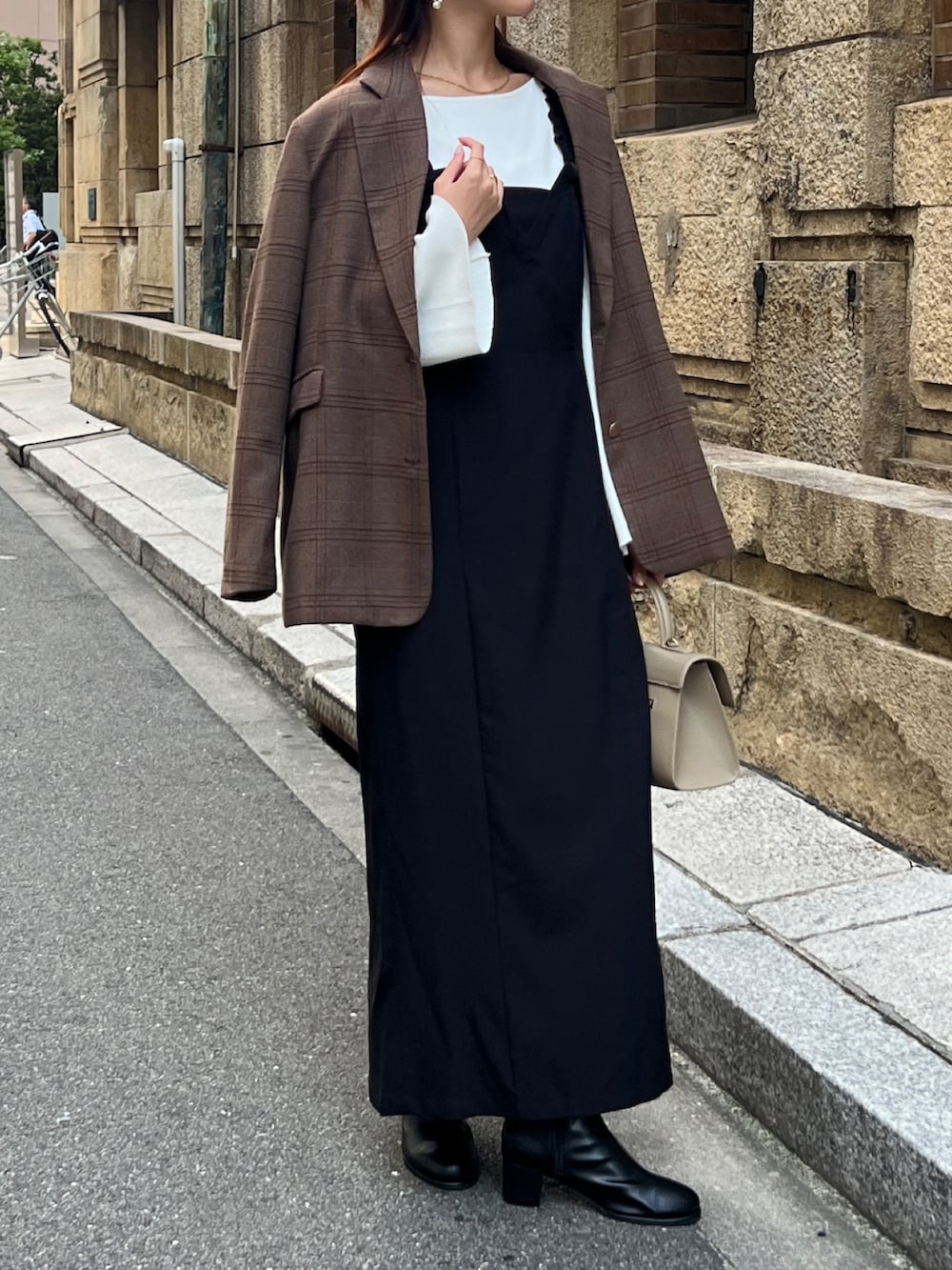 ブラウン系のテーラードジャケット、ブラック系のワンピース、ブラック系のブーツを着用したレディースの秋コーディネートの2枚目の写真