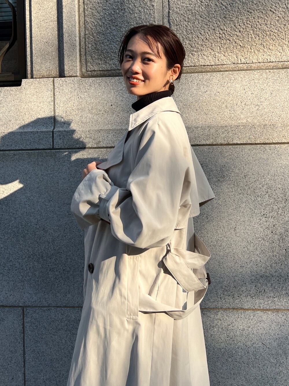 ベージュ系のトレンチコート、ブルー系のスカート、ブラック系のニット/セーターを着用したレディースの冬コーディネートの3枚目の写真