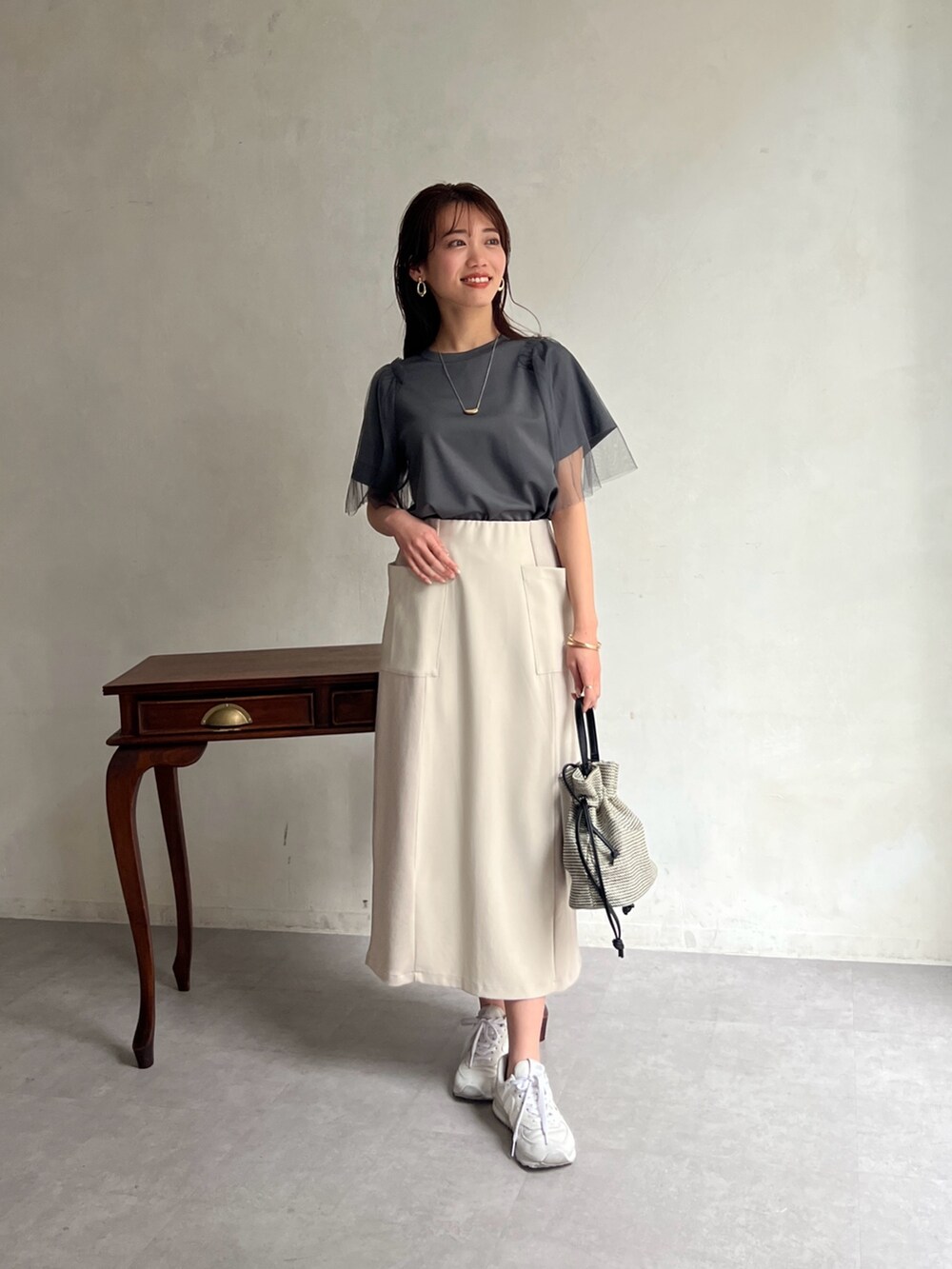 グレー系のTシャツ/カットソー、ホワイト系のスカート、ホワイト系のスニーカーを着用したレディースの春コーディネートの2枚目の写真