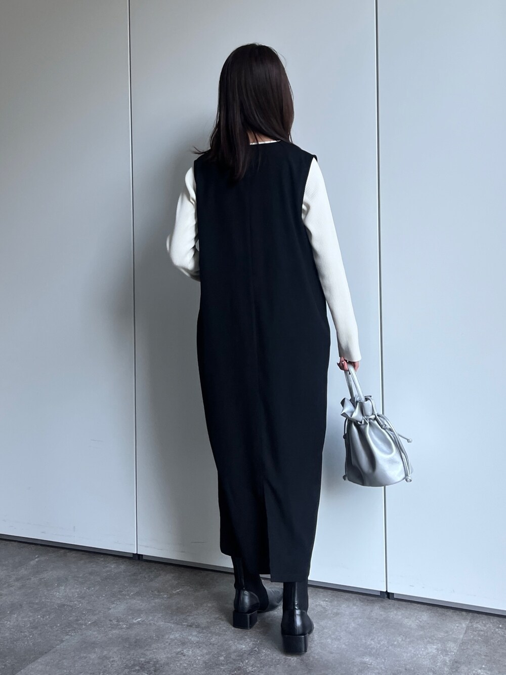 ブラック系のワンピース、シルバー系のショルダーバッグ、ブラック系のブーツを着用したレディースの冬コーディネートの3枚目の写真