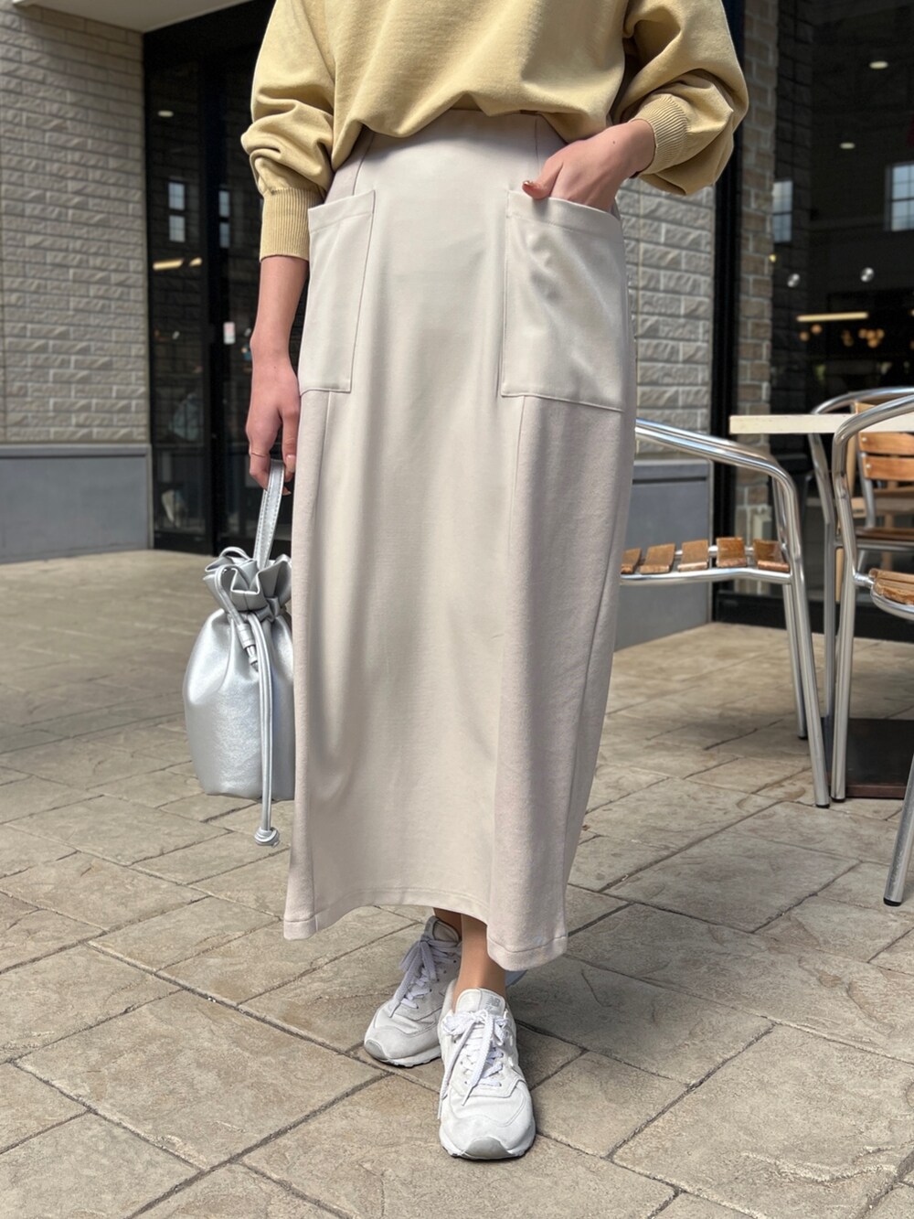 イエロー系のニット/セーター、ブルー系のテーラードジャケット、ホワイト系のスカートを着用したレディースの春コーディネートの4枚目の写真