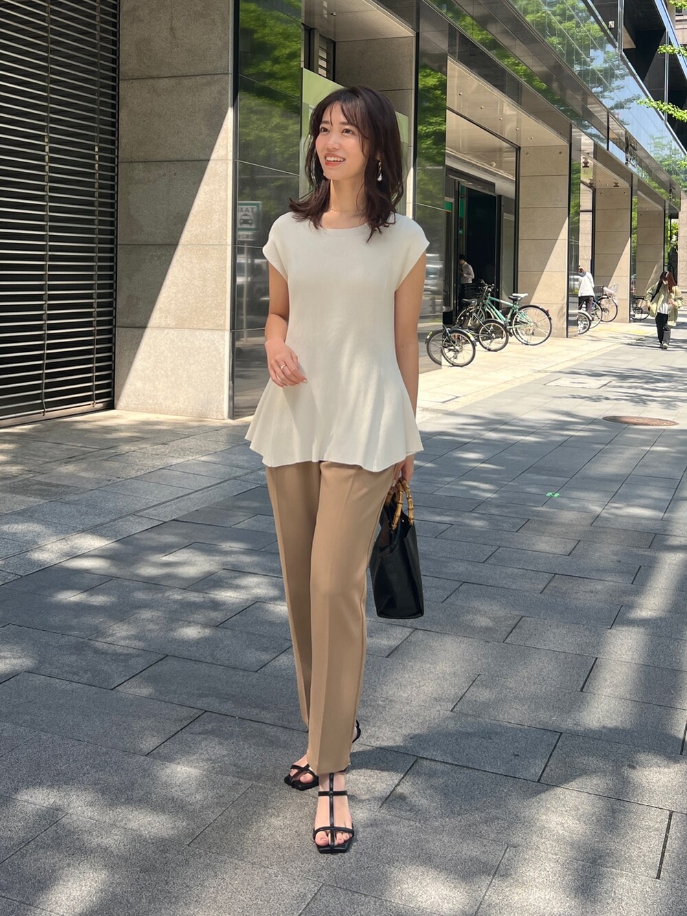 ホワイト系のニット/セーター、ベージュ系のその他パンツ、ブラック系のサンダルを着用したレディースの春コーディネートの2枚目の写真