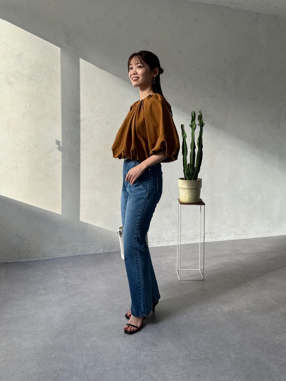 イエロー系のシャツ/ブラウス、ブルー系のデニムパンツ、ホワイト系のトートバッグを着用したレディースの春コーディネートの2枚目の写真