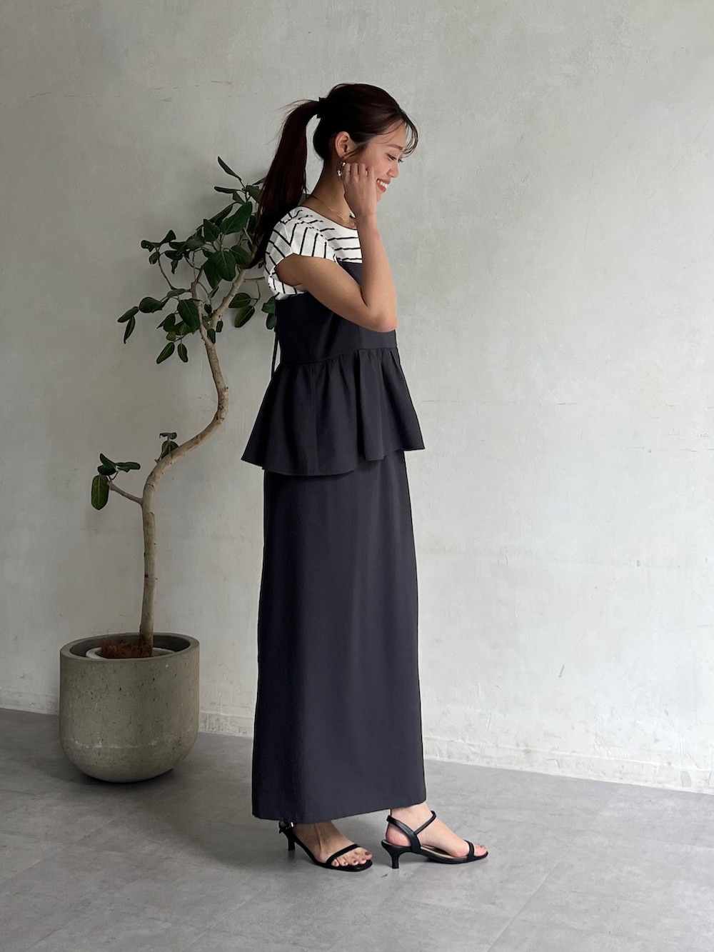 グレー系のワンピース、ブラック系のサンダル、ホワイト系のTシャツ/カットソーを着用したレディースの夏コーディネートの2枚目の写真