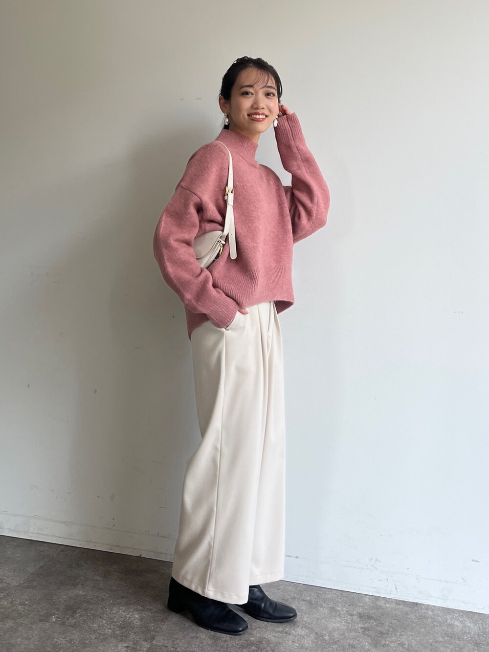 ピンク系のニット/セーター、ホワイト系のその他パンツ、ブラック系のブーツを着用したレディースの冬コーディネートの3枚目の写真