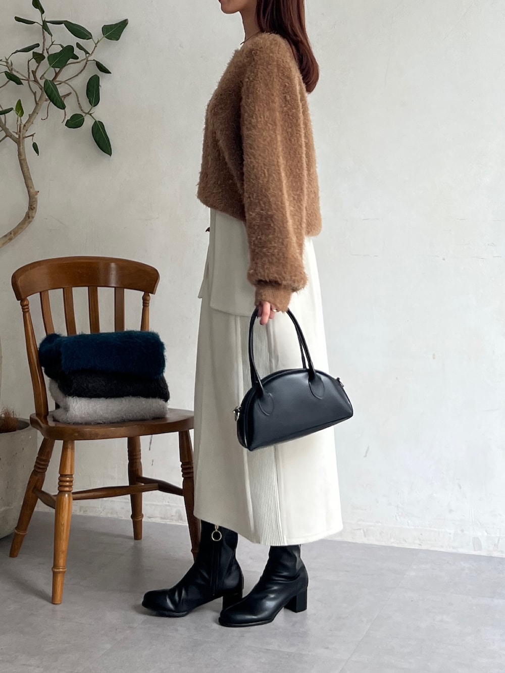 ブラウン系のニット/セーター、ホワイト系のスカート、ブラック系のブーツを着用したレディースの秋コーディネートの3枚目の写真