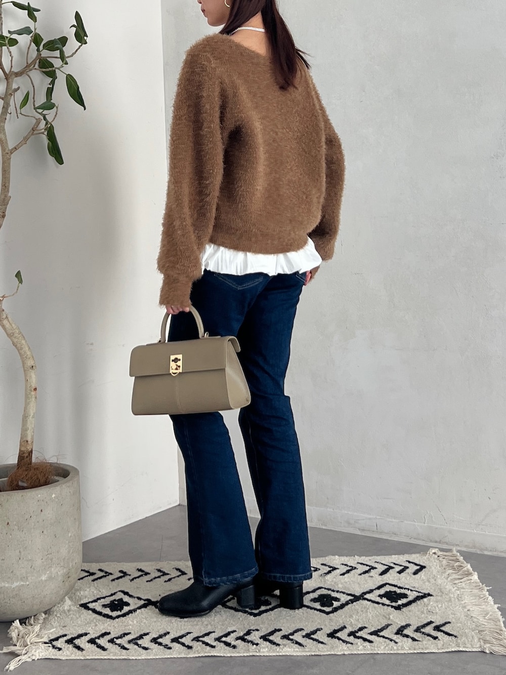 ブラウン系のニット/セーター、グレー系のカーディガン/ボレロ、ブルー系のデニムパンツを着用したレディースの秋コーディネートの2枚目の写真