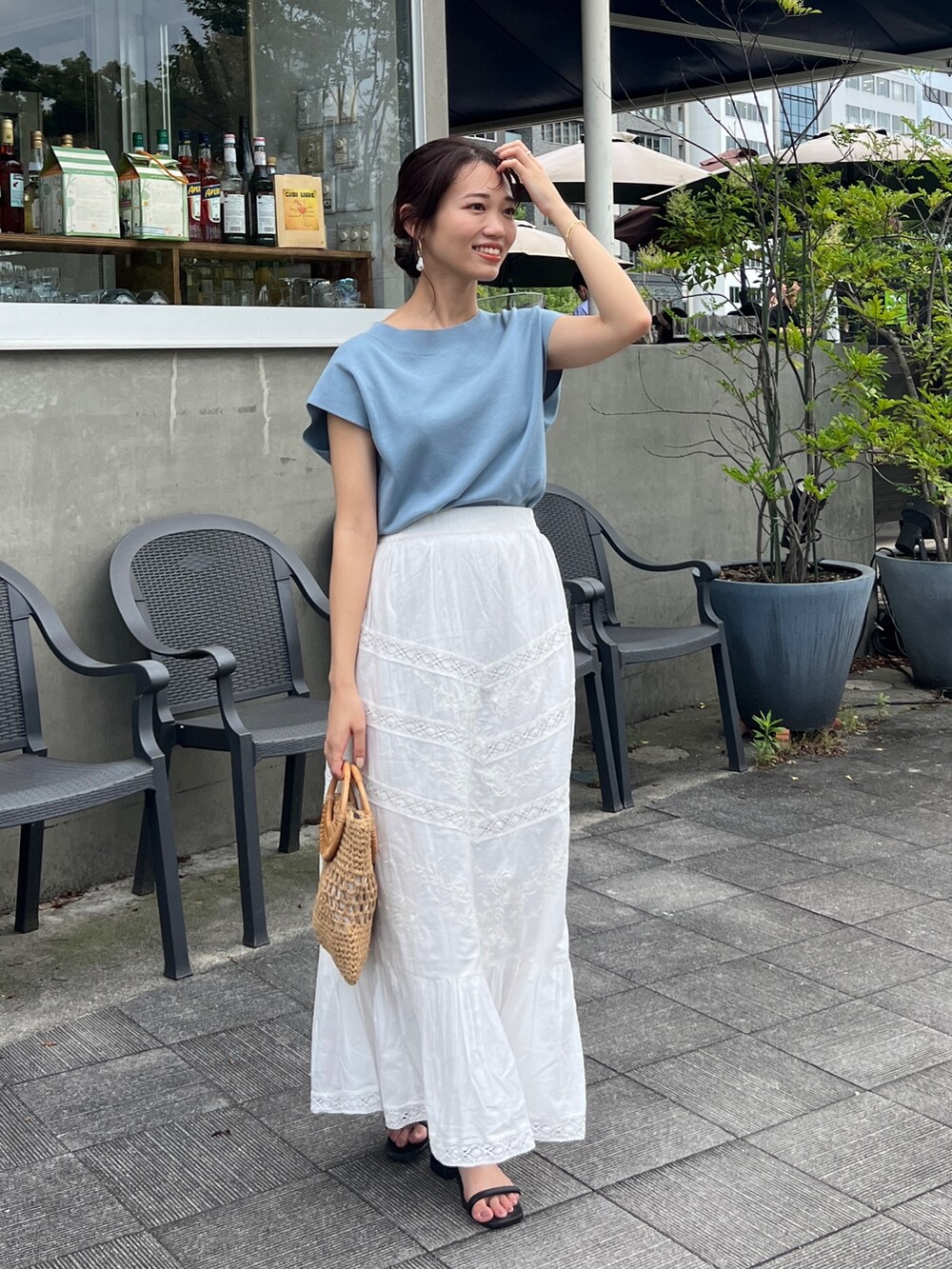 ブルー系のニット/セーター、ホワイト系のスカート、イエロー系のかごバッグを着用したレディースの夏コーディネートの2枚目の写真