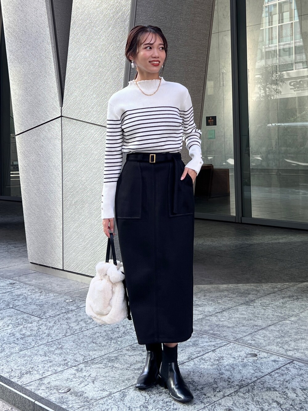 グリーン系のその他アウター、ブラック系のスカート、ホワイト系のトートバッグを着用したレディースの秋コーディネートの4枚目の写真