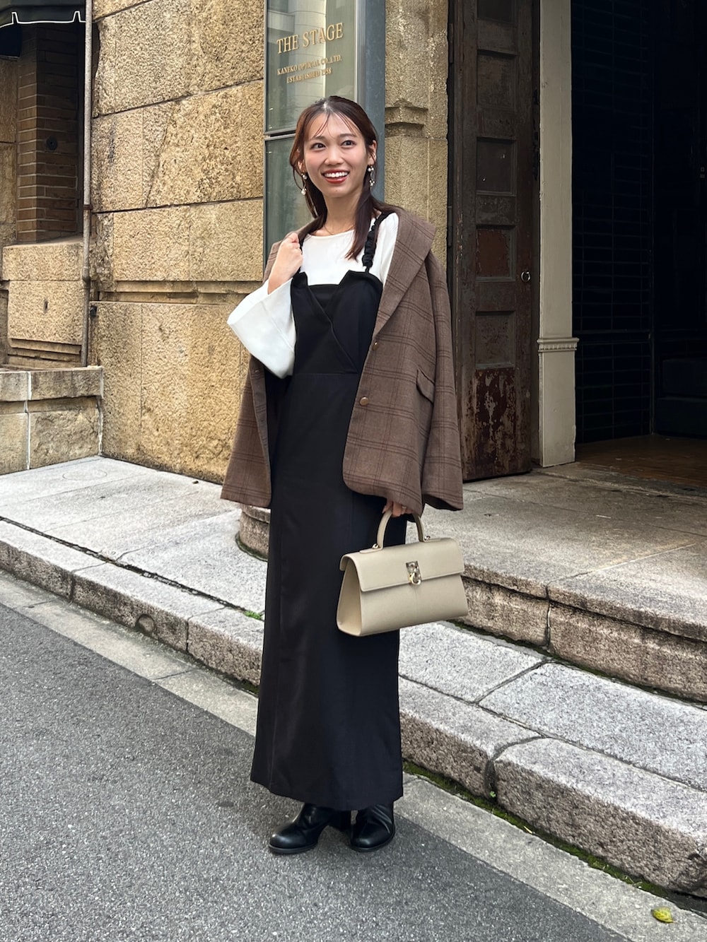 ブラウン系のテーラードジャケット、ブラック系のワンピース、ブラック系のブーツを着用したレディースの秋コーディネートの4枚目の写真