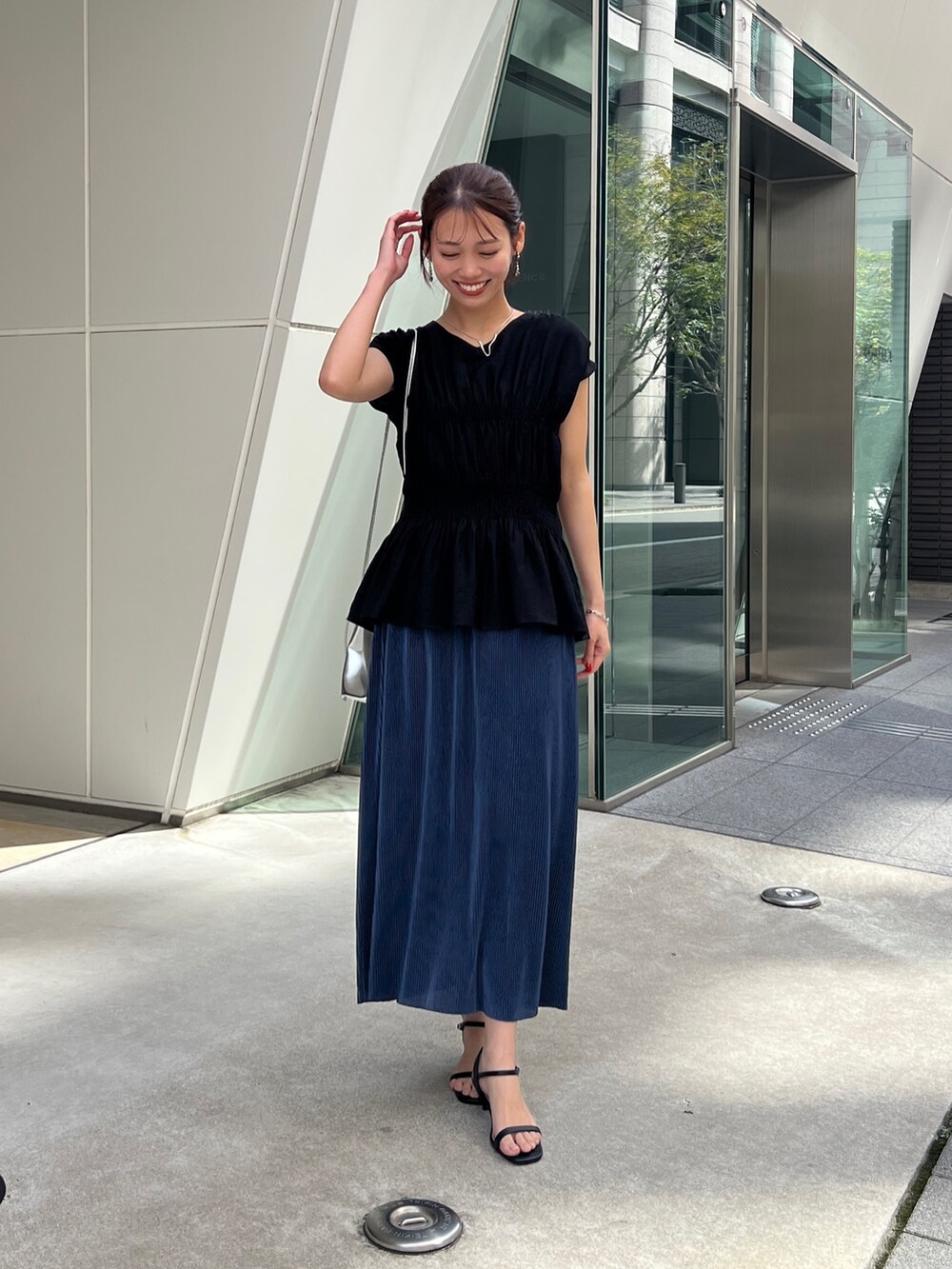 ブラック系のシャツ/ブラウス、ブルー系のスカート、シルバー系のトートバッグを着用したレディースの春コーディネートの2枚目の写真