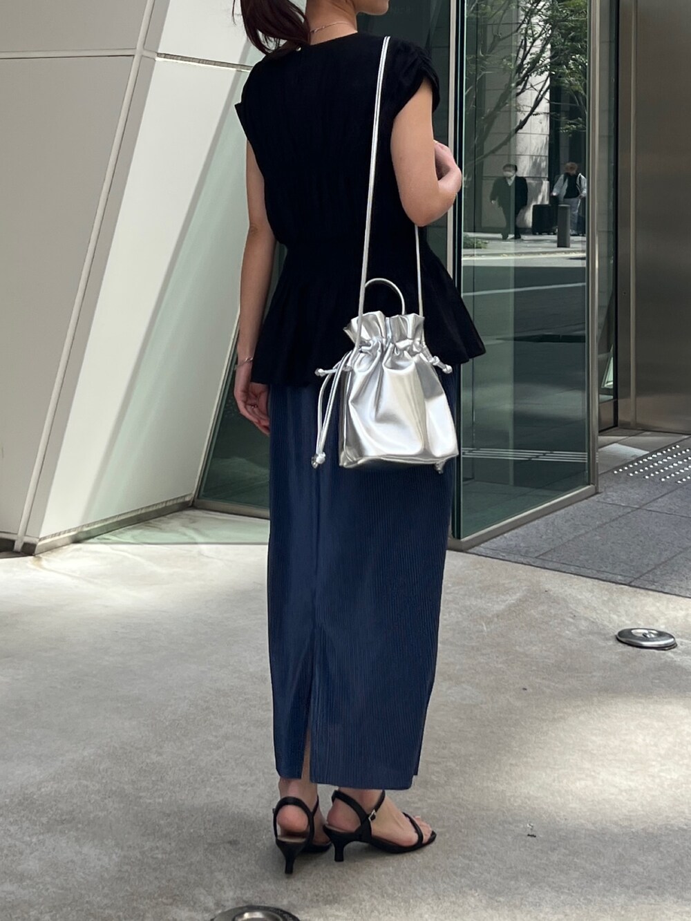 ブラック系のシャツ/ブラウス、ブルー系のスカート、シルバー系のトートバッグを着用したレディースの春コーディネートの3枚目の写真