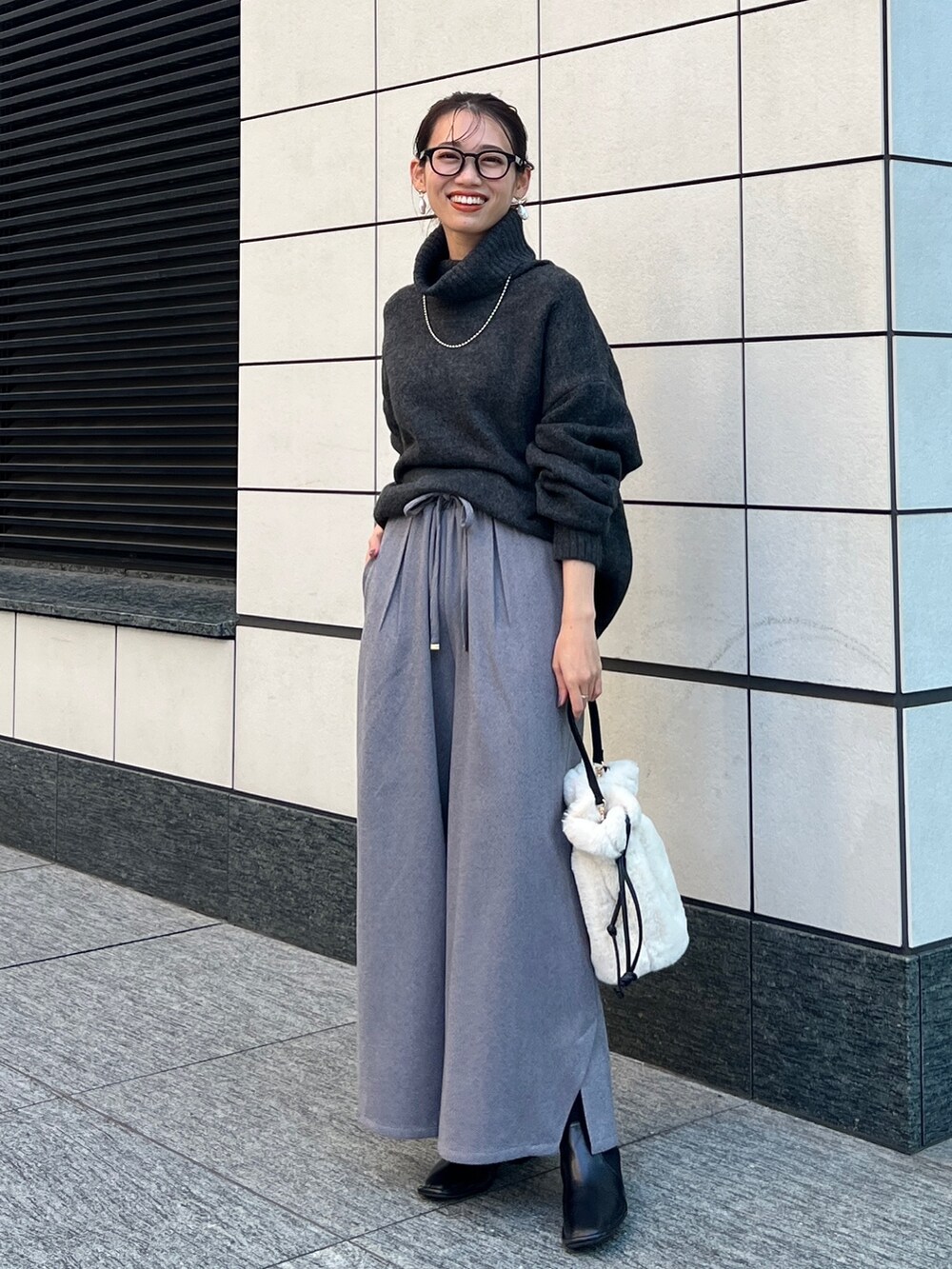 グレー系のニット/セーター、ブラック系のその他パンツ、ホワイト系のトートバッグを着用したレディースの秋コーディネートの2枚目の写真