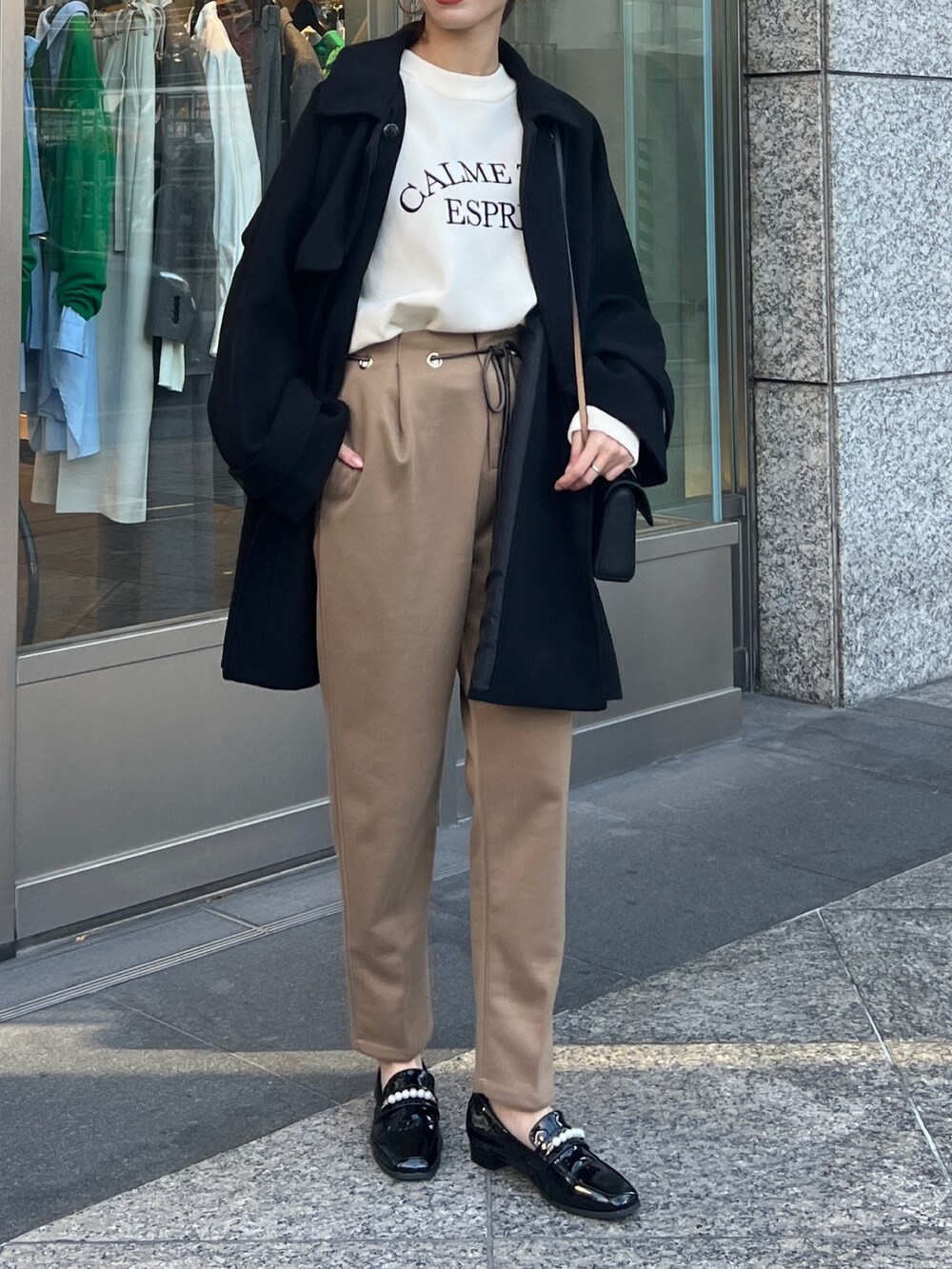 ブラック系のその他アウター、ホワイト系のニット/セーター、ベージュ系のその他パンツを着用したレディースの冬コーディネートの2枚目の写真