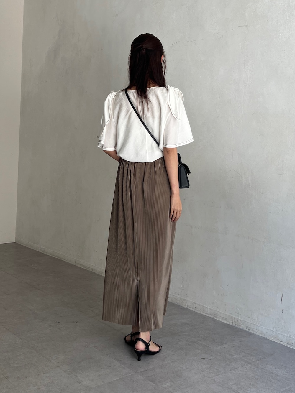 ホワイト系のシャツ/ブラウス、ベージュ系のスカート、ブラック系のサンダルを着用したレディースの夏コーディネートの3枚目の写真