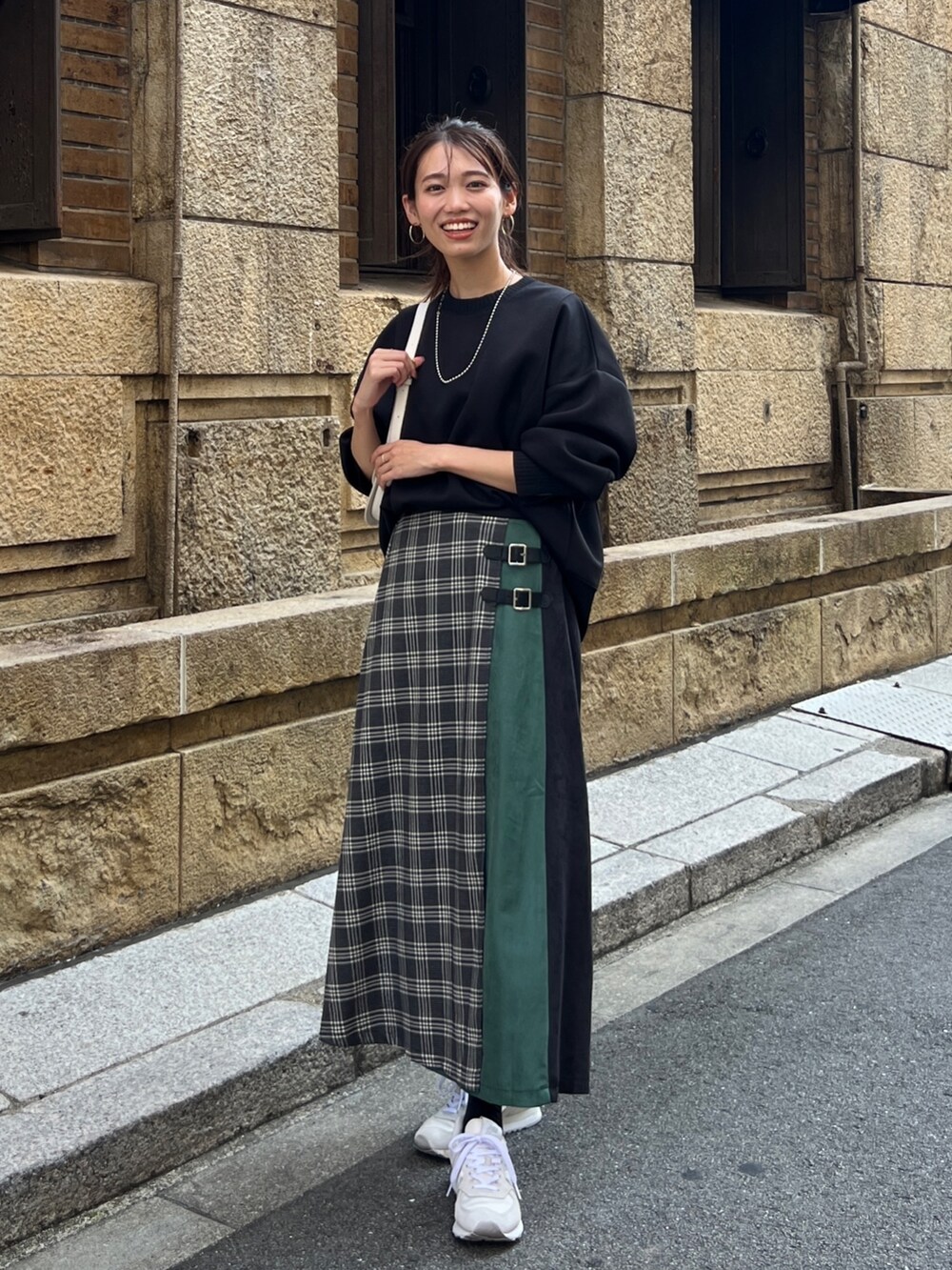 ブラック系のTシャツ/カットソー、ブラック系のスカート、ホワイト系のスニーカーを着用したレディースの秋コーディネートの2枚目の写真