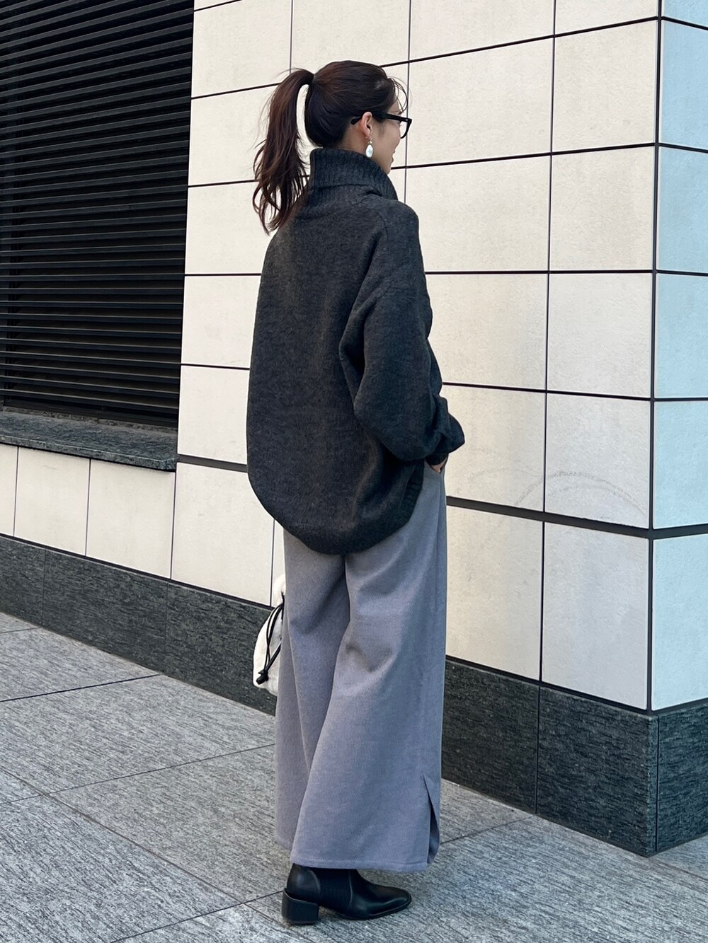 グレー系のニット/セーター、ブラック系のその他パンツ、ホワイト系のトートバッグを着用したレディースの秋コーディネートの3枚目の写真