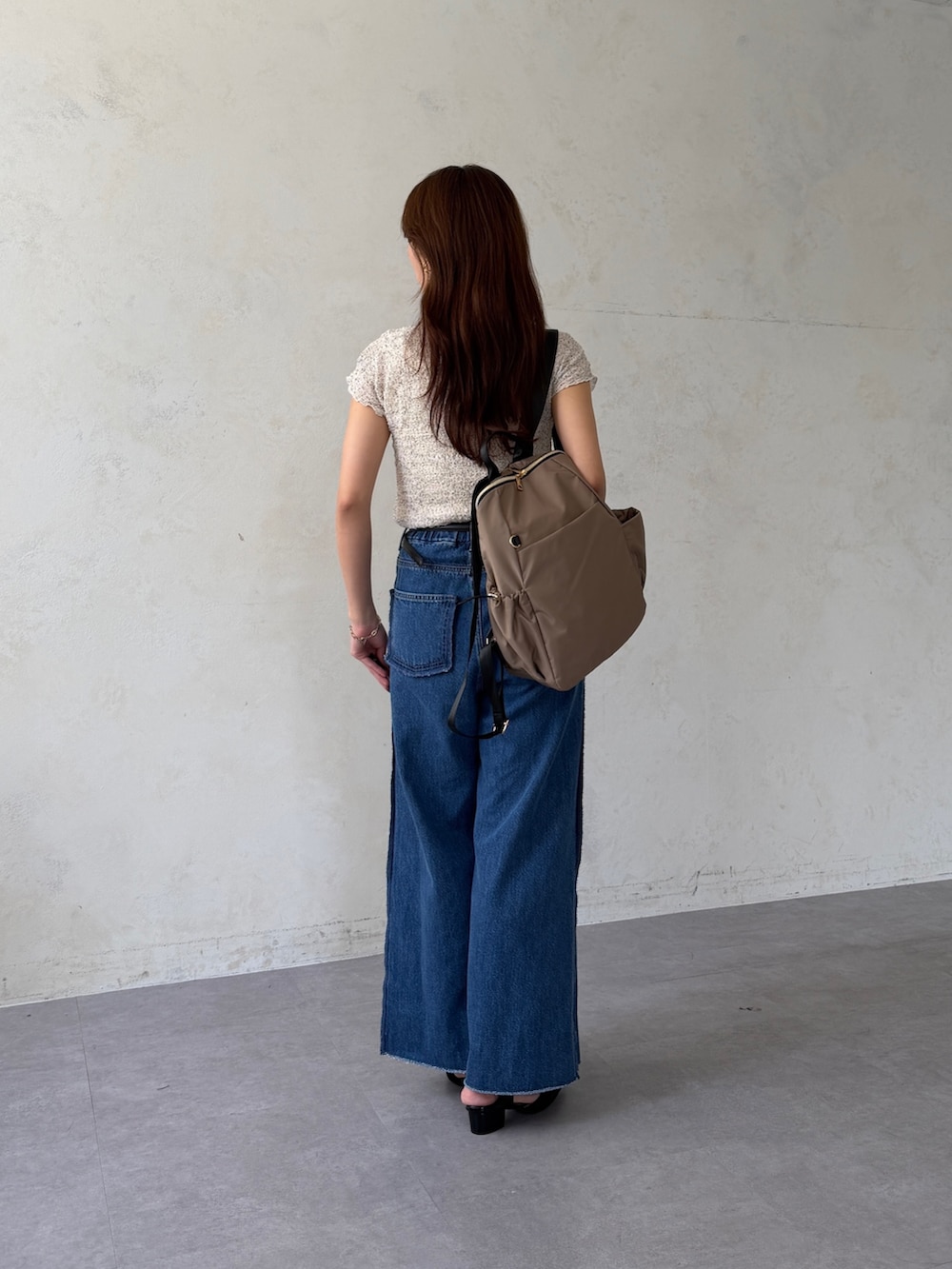 ホワイト系のTシャツ/カットソー、ベージュ系のバックパック/リュック、ブラック系のパンプスを着用したレディースの夏コーディネートの3枚目の写真