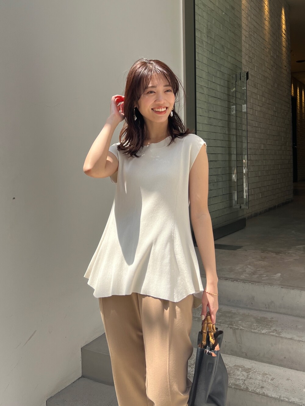 ホワイト系のニット/セーター、ベージュ系のその他パンツ、ブラック系のサンダルを着用したレディースの春コーディネートの3枚目の写真