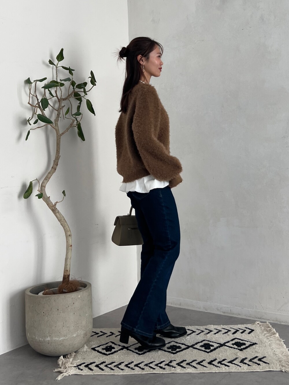 ブラウン系のニット/セーター、グレー系のカーディガン/ボレロ、ブルー系のデニムパンツを着用したレディースの秋コーディネートの4枚目の写真