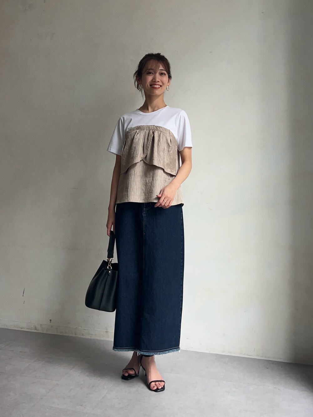 ベージュ系のTシャツ/カットソー、ブルー系のデニムスカート、ブラック系のシューズを着用したレディースの春コーディネートの2枚目の写真