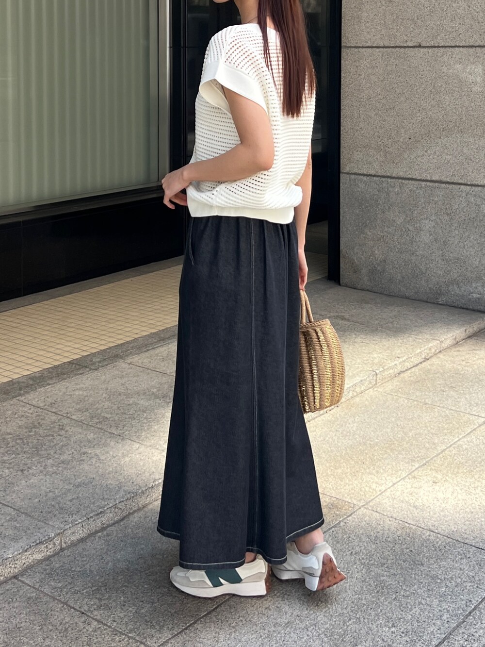 ホワイト系のニット/セーター、ブラック系のスカート、ベージュ系のかごバッグを着用したレディースの春コーディネートの4枚目の写真