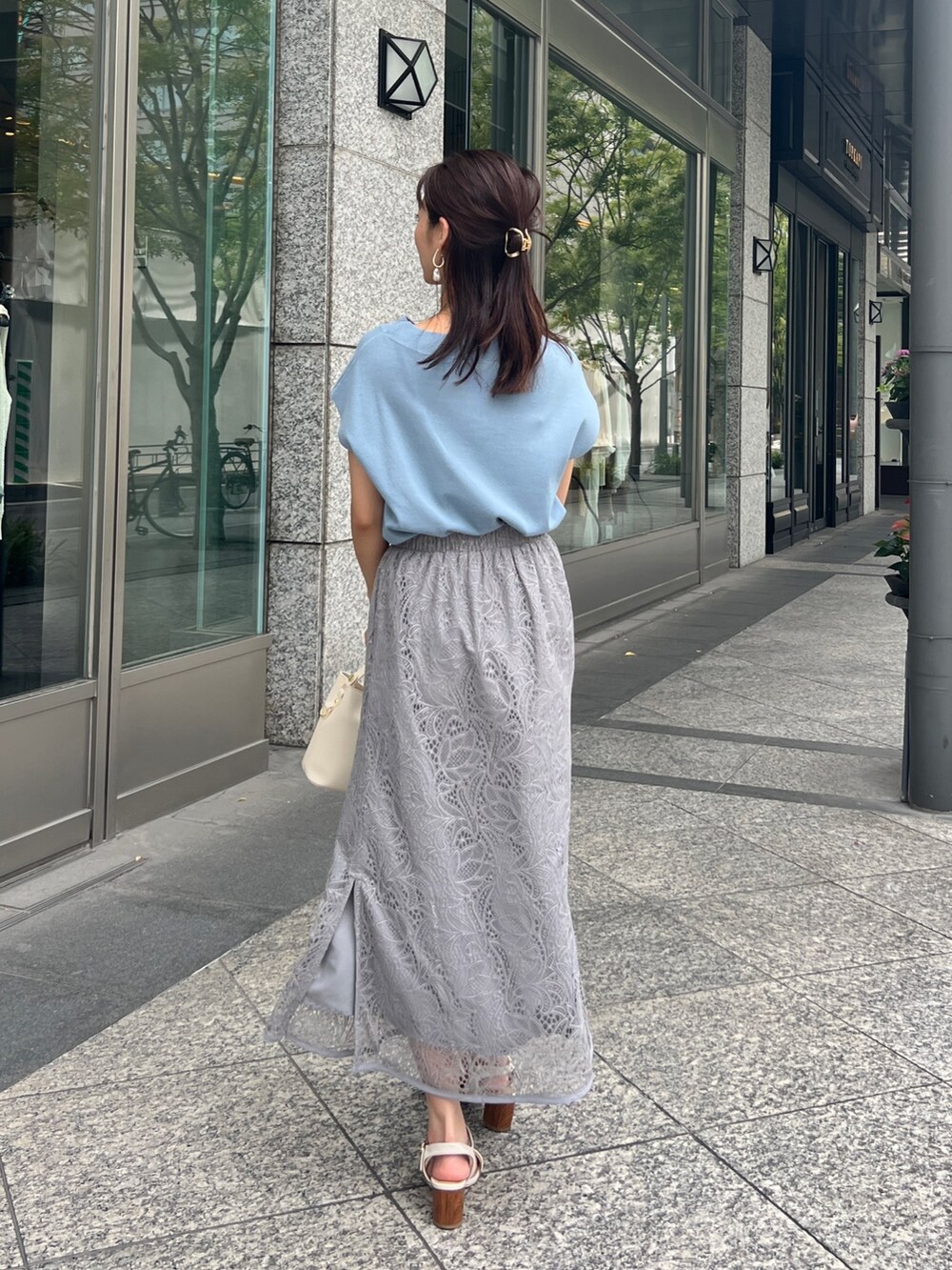 ブルー系のニット/セーター、グレー系のスカート、ホワイト系のショルダーバッグを着用したレディースの夏コーディネートの3枚目の写真