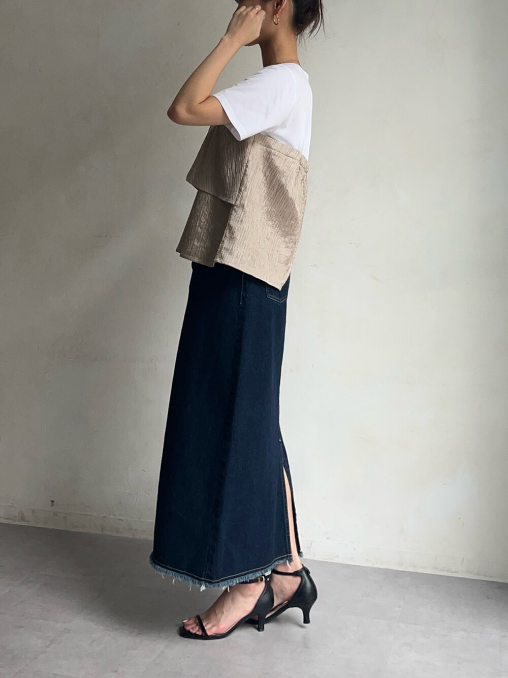 ベージュ系のTシャツ/カットソー、ブルー系のデニムスカート、ブラック系のシューズを着用したレディースの春コーディネートの3枚目の写真