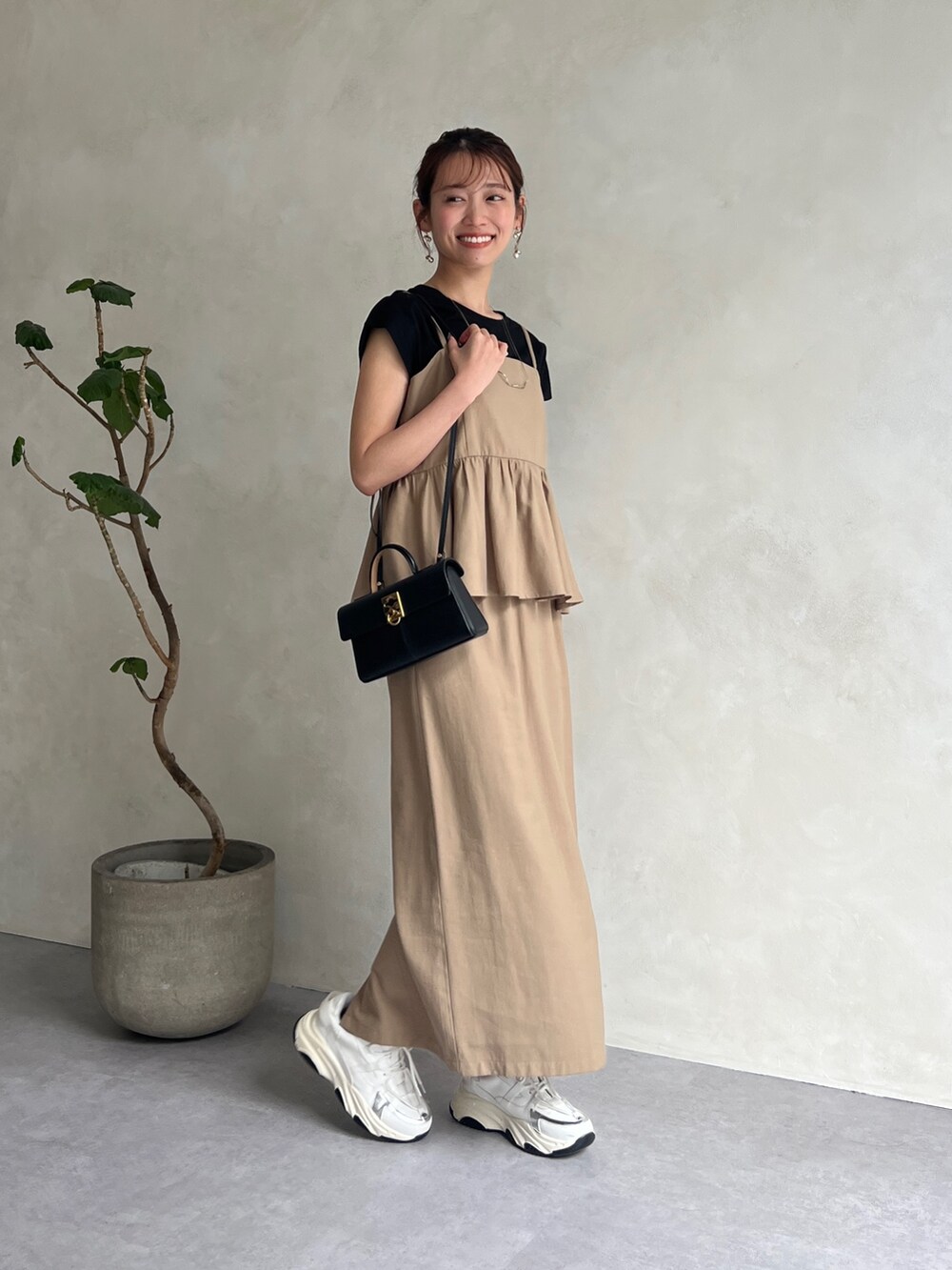 ベージュ系のワンピース、ブラック系のTシャツ/カットソー、ホワイト系のスニーカーを着用したレディースの夏コーディネートの2枚目の写真