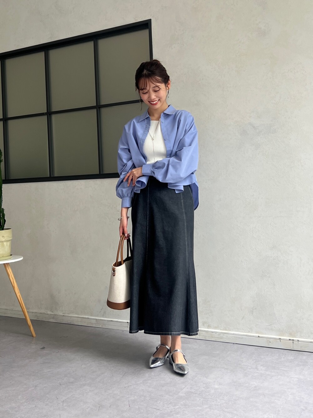 ブルー系のシャツ/ブラウス、ホワイト系のニット/セーター、ブラック系のスカートを着用したレディースの春コーディネートの5枚目の写真