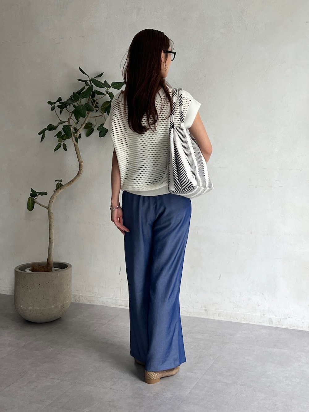 ホワイト系のニット/セーター、ブラック系のトートバッグ、ブルー系のその他パンツを着用したレディースの夏コーディネートの2枚目の写真