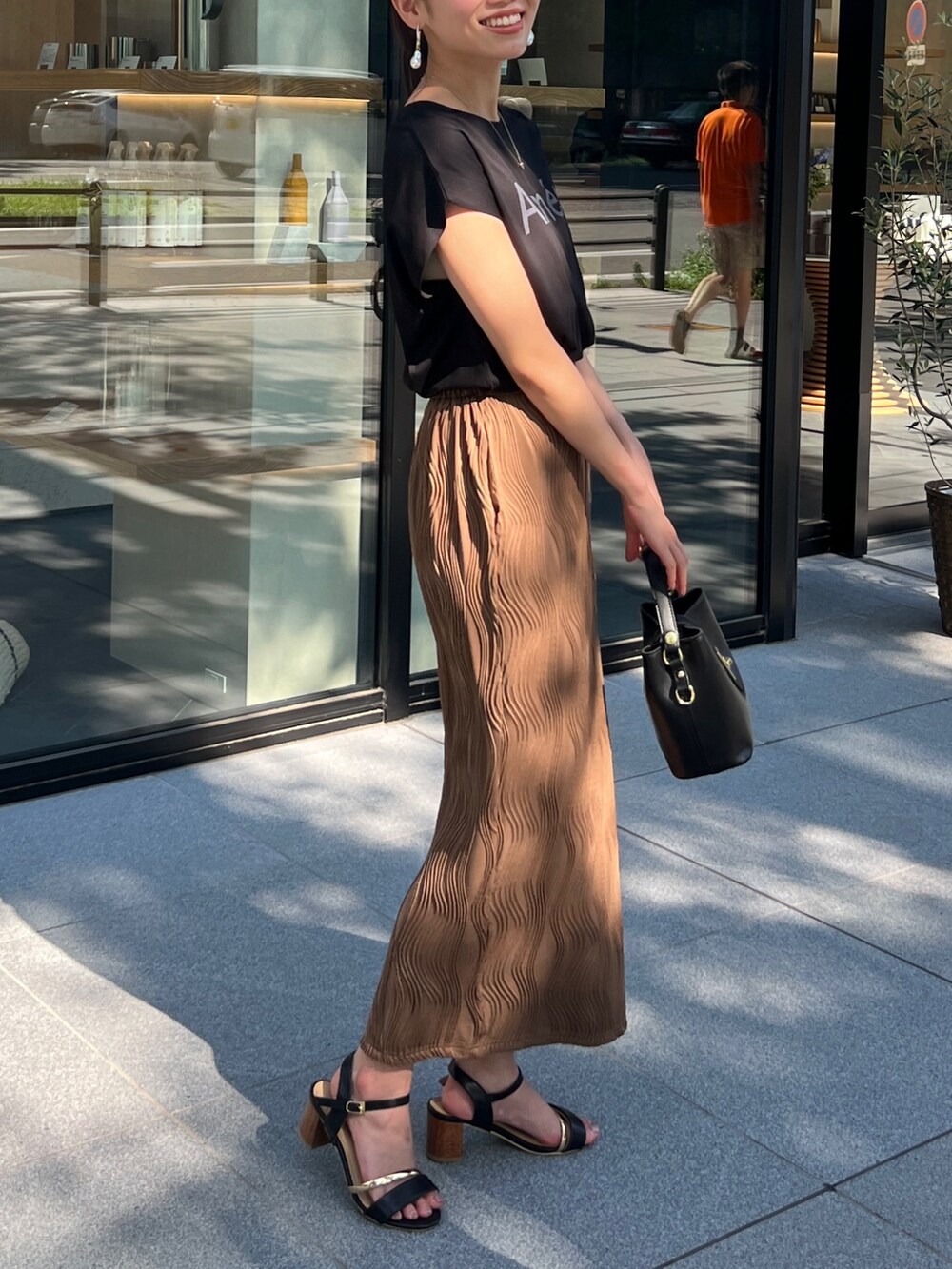 ブラック系のTシャツ/カットソー、ブラウン系のスカート、ブラック系のショルダーバッグを着用したレディースの夏コーディネートの2枚目の写真