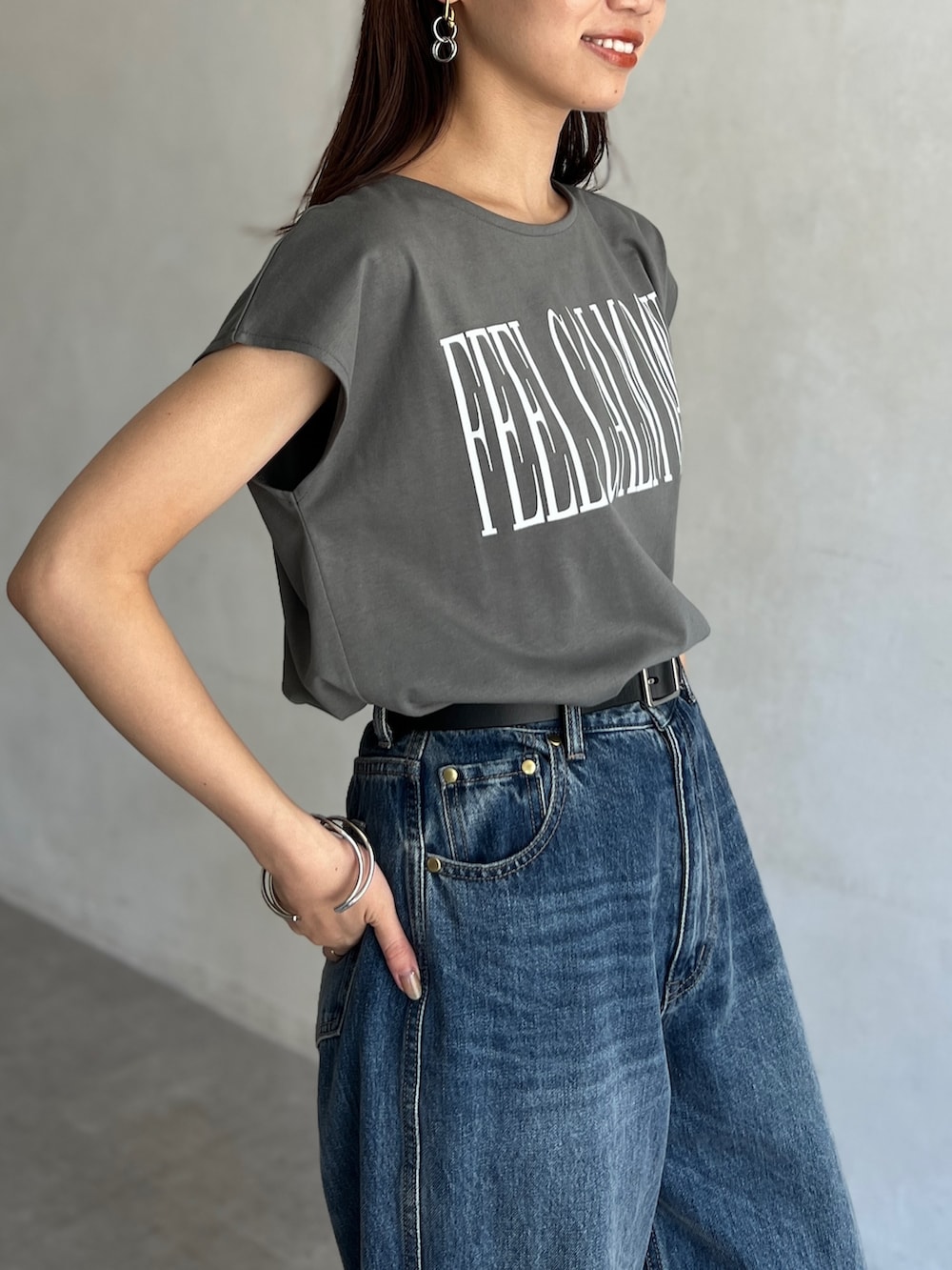 グリーン系のTシャツ/カットソー、ブルー系のデニムパンツ、シルバー系のピアス（両耳用）を着用したレディースの夏コーディネートの4枚目の写真