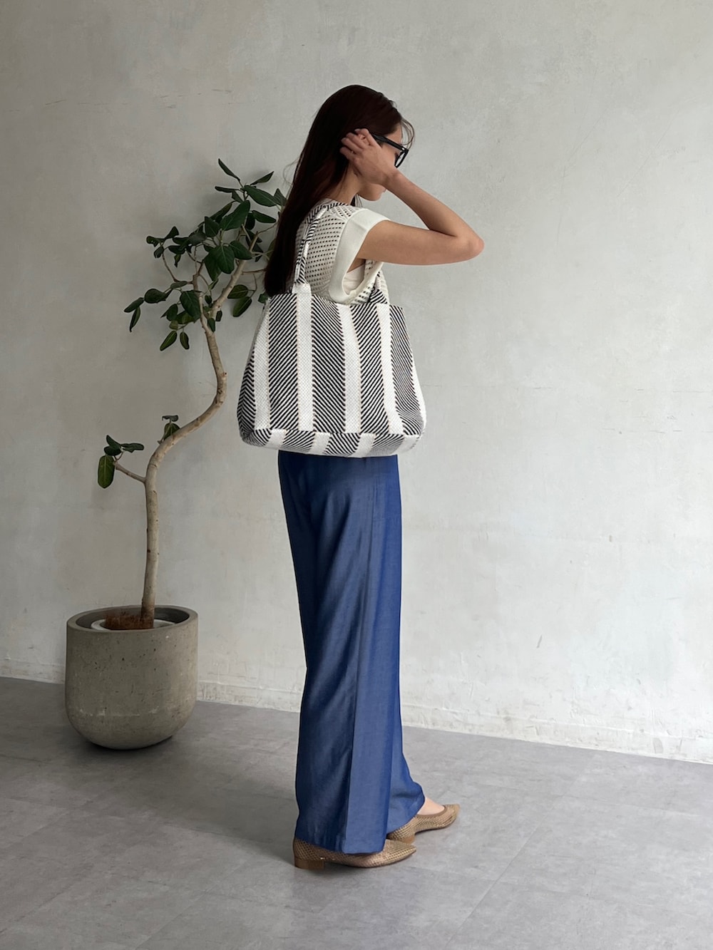 ホワイト系のニット/セーター、ブラック系のトートバッグ、ブルー系のその他パンツを着用したレディースの夏コーディネートの3枚目の写真