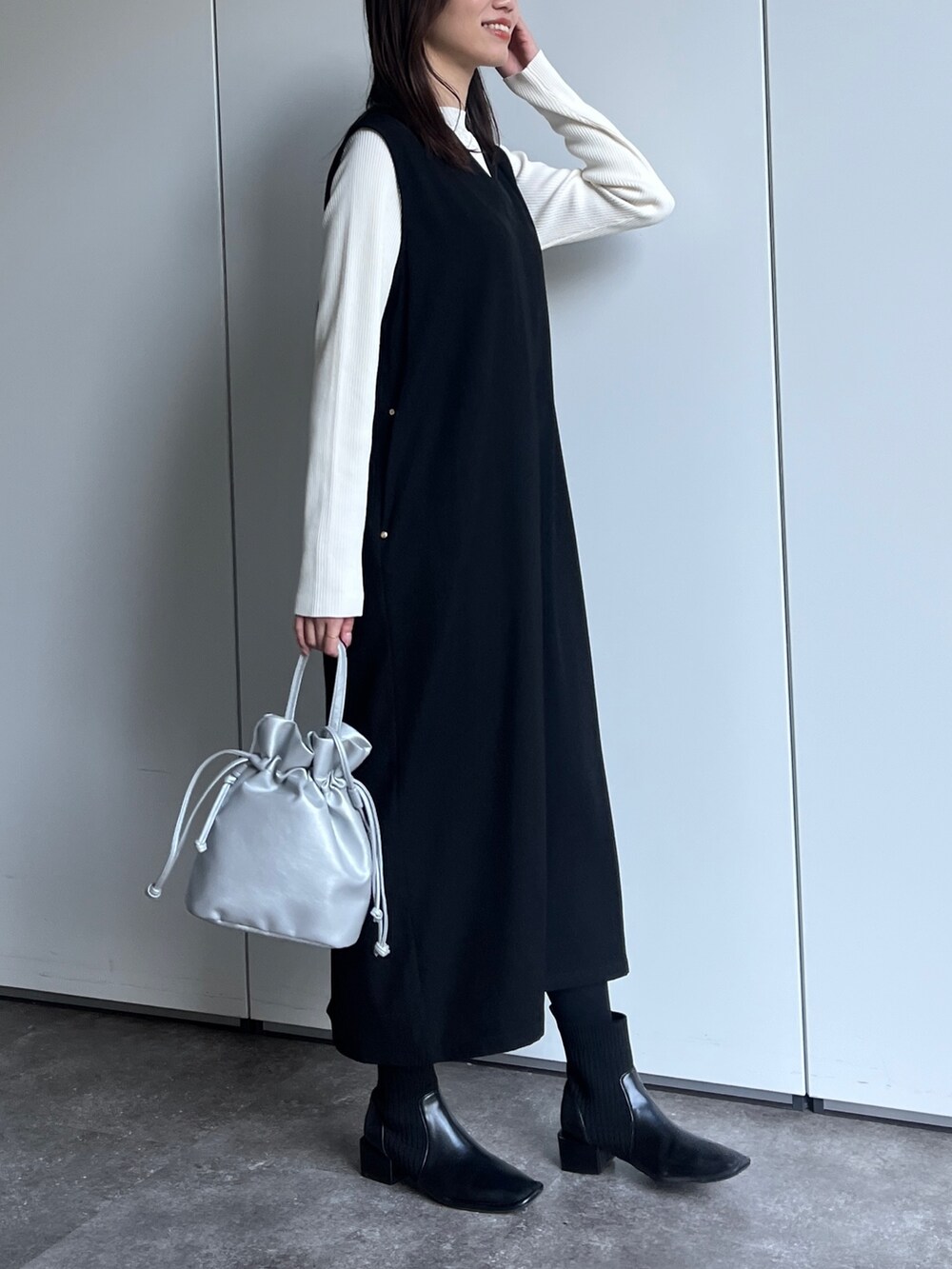 ブラック系のワンピース、シルバー系のショルダーバッグ、ブラック系のブーツを着用したレディースの冬コーディネートの2枚目の写真