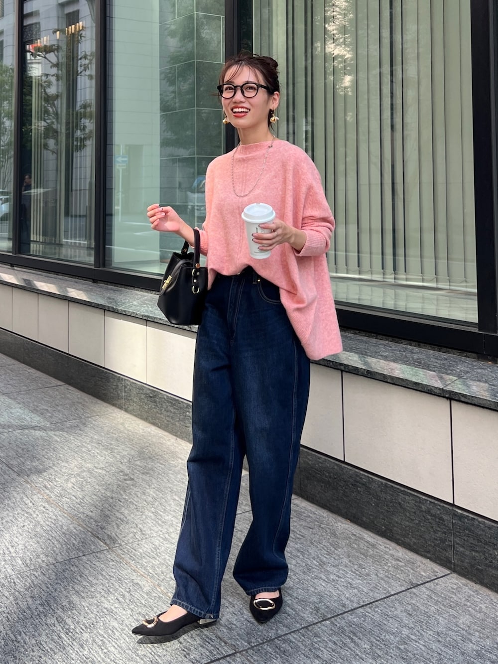 オレンジ系のニット/セーター、ブラック系のショルダーバッグ、ブルー系のデニムパンツを着用したレディースの秋コーディネートの2枚目の写真