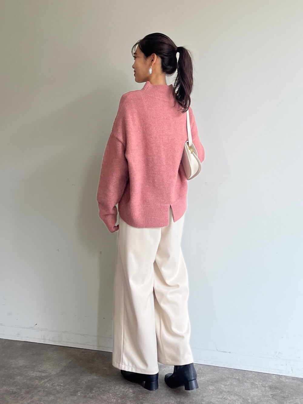 ピンク系のニット/セーター、ホワイト系のその他パンツ、ブラック系のブーツを着用したレディースの冬コーディネートの2枚目の写真