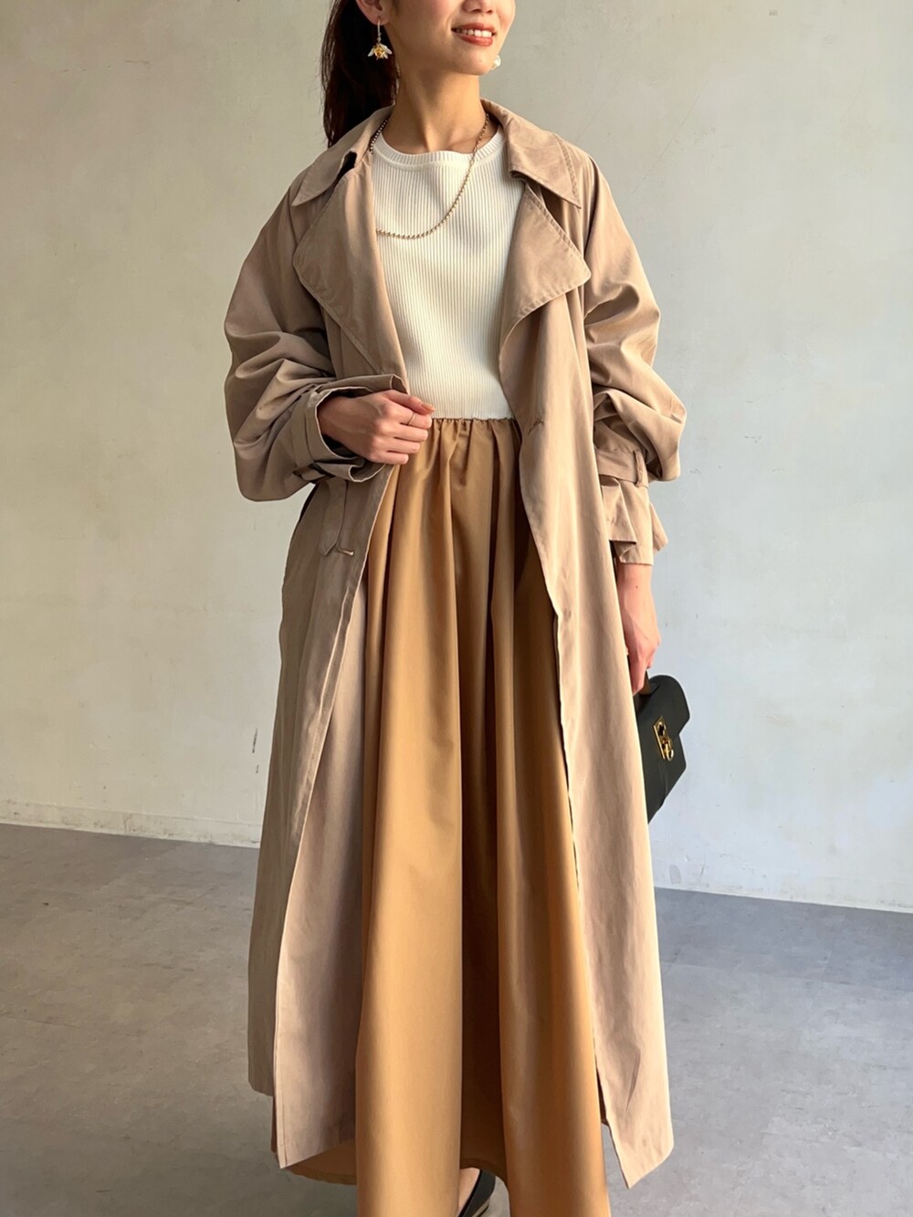 ベージュ系のトレンチコート、イエロー系のワンピース/ドレス、ブラック系のパンプスを着用したレディースの冬コーディネートの3枚目の写真