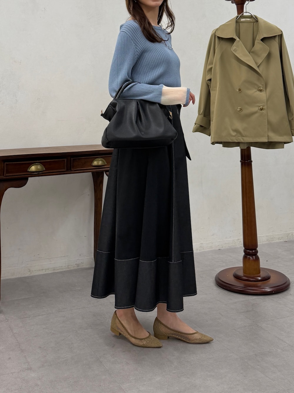 ブルー系のニット/セーター、ブラック系のスカートを着用したレディースの春コーディネートの4枚目の写真