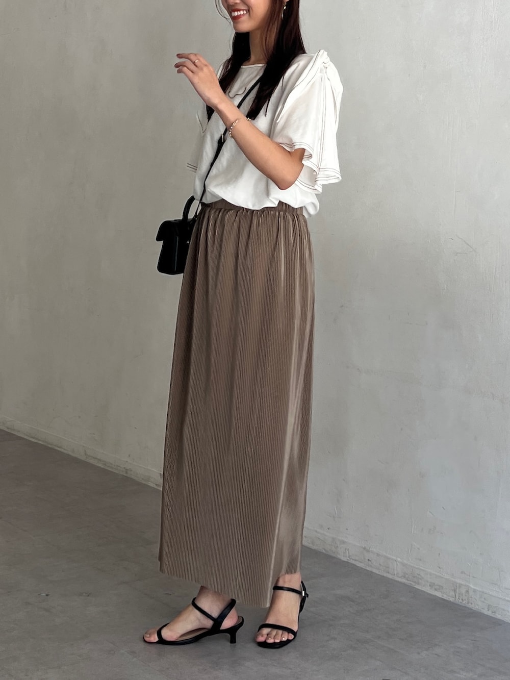 ホワイト系のシャツ/ブラウス、ベージュ系のスカート、ブラック系のサンダルを着用したレディースの夏コーディネートの2枚目の写真