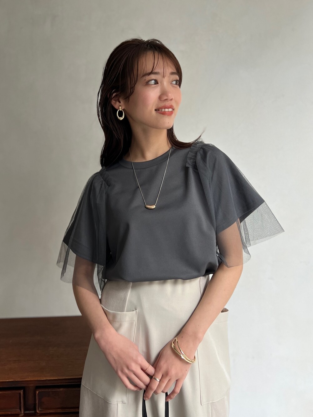 グレー系のTシャツ/カットソー、ホワイト系のスカート、ホワイト系のスニーカーを着用したレディースの春コーディネートの3枚目の写真