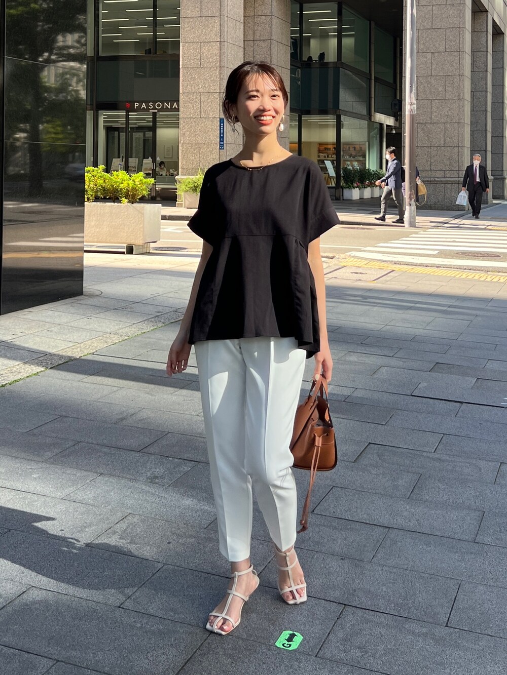 ブラック系のシャツ/ブラウス、ホワイト系のパンツ、ブラウン系のバッグを着用したレディースの春コーディネートの2枚目の写真