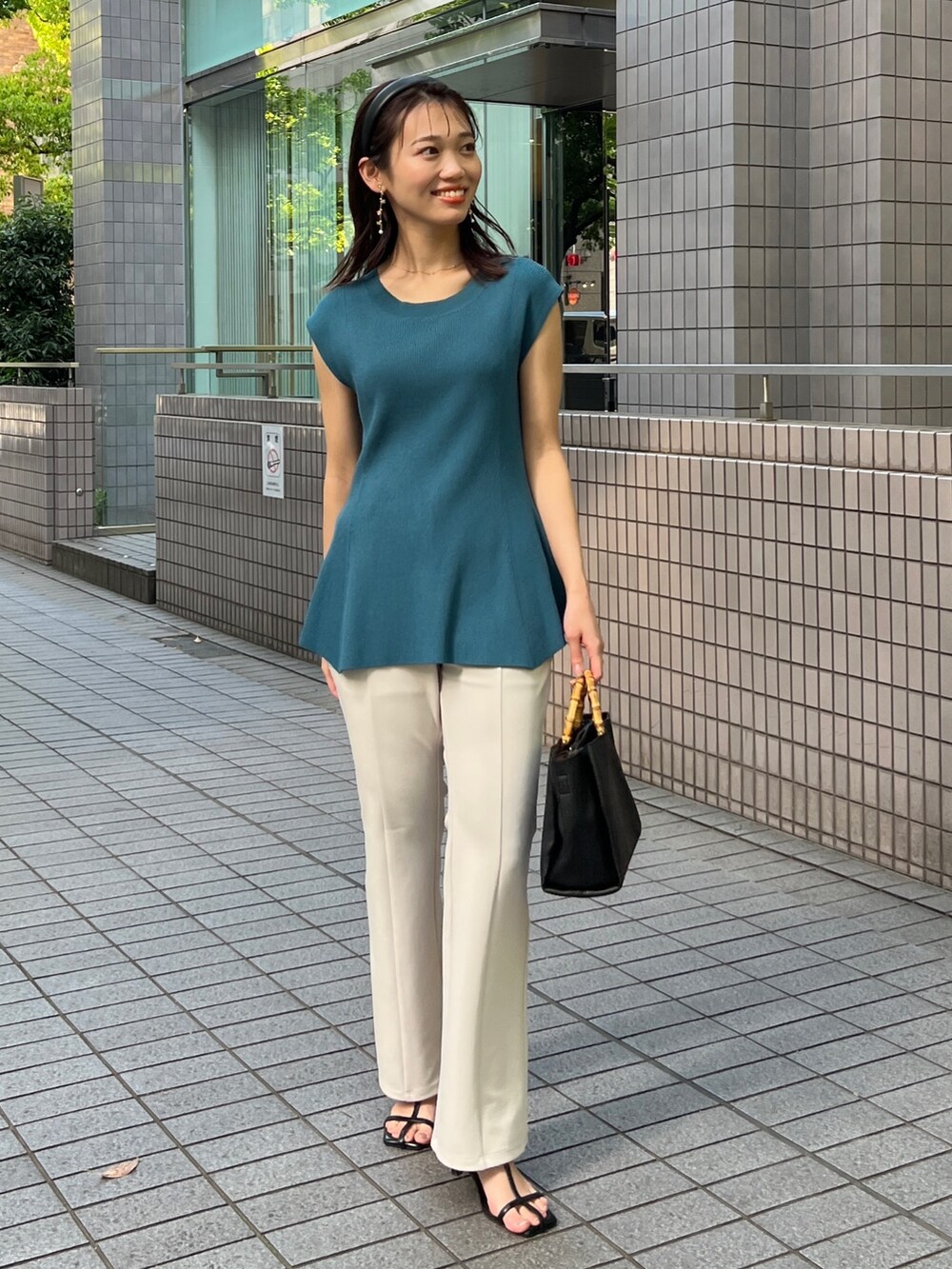 グリーン系のニット/セーター、ブラック系のサンダル、ホワイト系のパンツを着用したレディースの春コーディネートの2枚目の写真